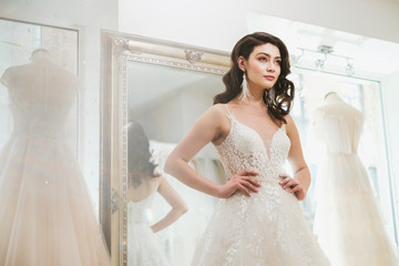 Beautifu bride choosing wedding dress in a wedding salon