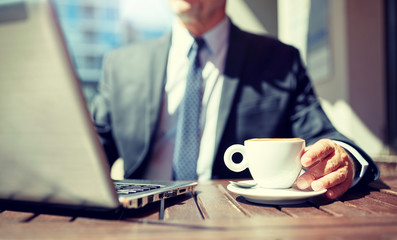 business, hot drinks, break and people and concept - senior businessman with laptop computer drinking coffee from espresso cup outdoors