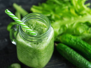 Close-up of green smoothie in a glass jar with ingredients on a dark wooden table