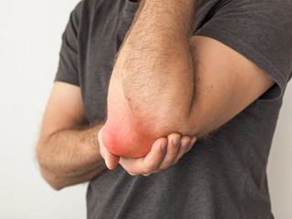 man holds a painful elbow