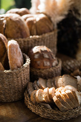 Bread from different types of flour of cereal seeds. Baking in straw baskets on a large wooden table. Rustic style.