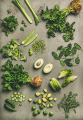 Healthy vegan ingredients layout. Flat-lay of whole and cut green vegetables and herbs over concrete background, top view. Vegetarian, weight loss, raw, spring light food, clean eating concept