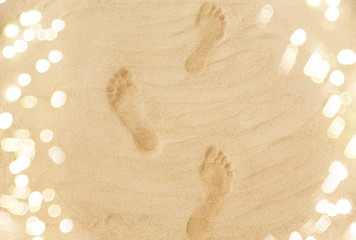 summer vacation concept - trail of footprints in sand on beach
