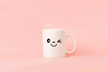 Cup of coffee on pink background with happy smile face on mug