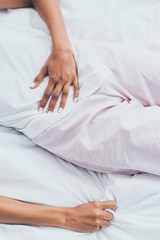 cropped view of african american woman suffering from abdominal pain while lying in bed