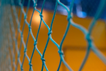 Looing through a blue net to a yellow and blue background blurred out. Games, sports, goals, or concepts.