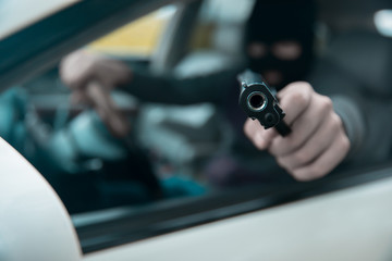 man driving  car hand gun