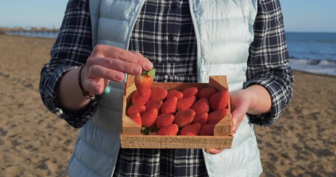 Female hands holding wooden box full of ripe straberry