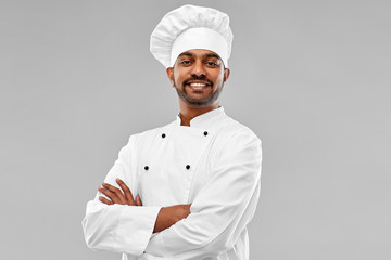 cooking, profession and people concept - happy male indian chef in toque over grey background
