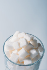 Fototapeta na wymiar white sweet sugar cubes in glass on grey background