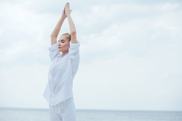 attractive girl with closed eyes practicing yoga and standing with praying hands