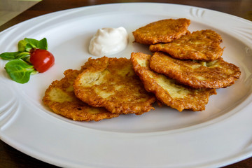 Potato pancake dranik with sour cream on a white plate, a traditional dish.