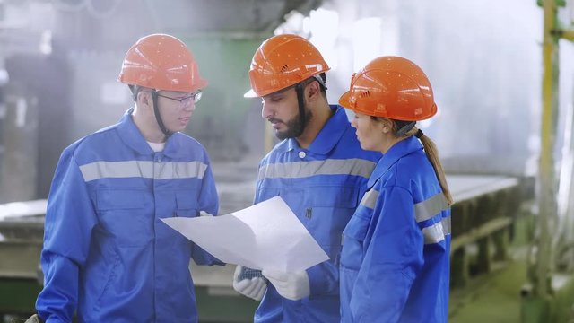Tilt up shot of foreign engineers visiting factory for experience exchange, discussing and disputing about scheme of mechanism