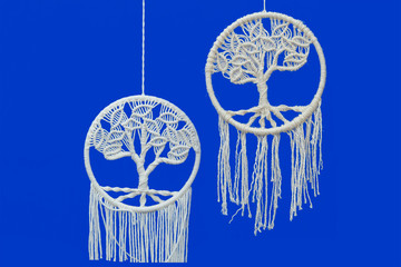Two knitted dream catchers on blue background.  Front view