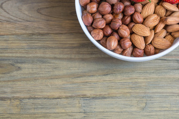 Plate of fresh strawberreis and almond, hazelnut on wooden background. Vegetarian breakfast