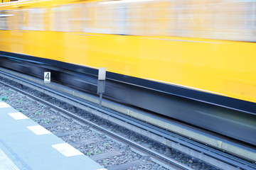 Fototapeta premium Fast moving yellow train in Berlin Germany - motion exposure