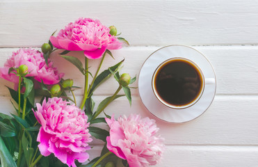 Pink peony flowers on white wooden table. womans day or wedding background. Cup of coffee.