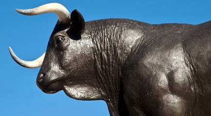 Typical black bull sculpture in front of blue sky