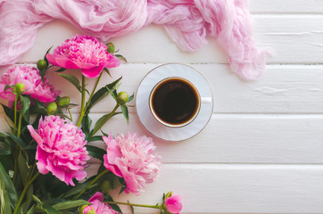 Pink peony flowers on white wooden table. womans day or wedding background. Cup of coffee.