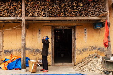 Obraz na płótnie Canvas Unrecognisable hmong woman adjusting her head scarf in front of a traditional hmong building in Ha Giang Province, Northern Vietnam.