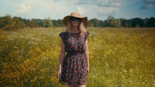 Romantic Female Walking.Girl Relaxing.Girl Walks Through Field.Pretty Ledy In Dress.Girl In Sunglasse. Enjoing.Happy Woman Walking In Summer Field.Wicker Hat.Woman In Hat Walking On Field.Woman In Hat