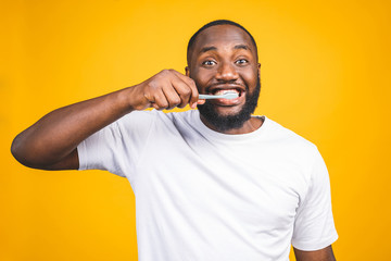 Man with tooth brush. Image of young shirtless African man holding a toothbrush with toothpaste and smiling while standing against yellow background.