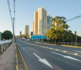 Brazilian large avenue with directional arrows on the street. Electric poles and few buildings on background. Ceara Avenue at the capital city, Campo Grande - MS, Brazil.
