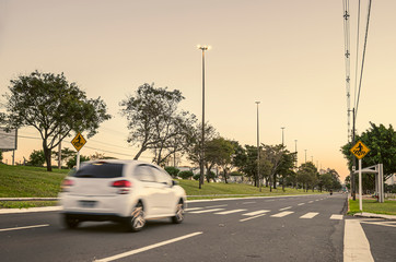 Car going fast on a avenue close to the crosswalk. Vehicle exceeding the maximum speed of the street. Crosswalk with pedestrians sign. Photo at the Afonso Pena avenue, Campo Grande - MS, Brazil.