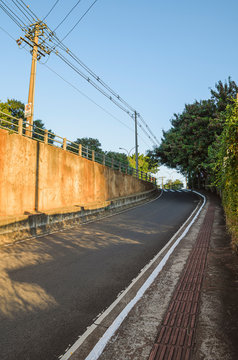 Curved side street, entrance to the high viaduct. Inclined street access to the higher lane. Sidewalk with tactile floor for accessibility of the visually impaired. Street of Campo Grande MS, Brazil.