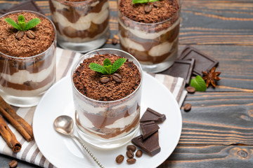 Classic tiramisu dessert in a glass on wooden background