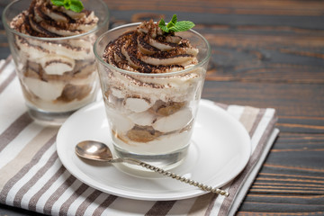 Classic tiramisu dessert in a glass on wooden background
