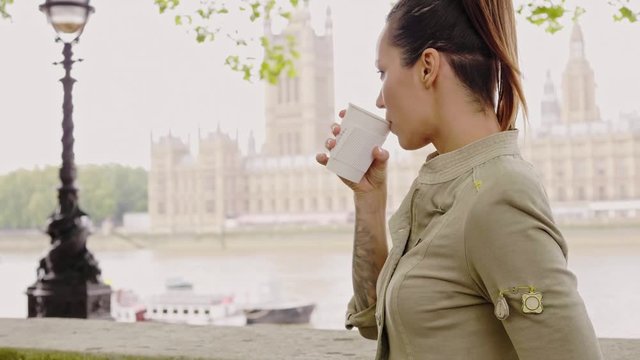 Woman drinking coffee against House of Parliament in London