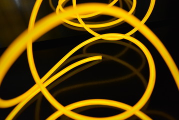 The original yellow lighting of thick electoluminescent wires and lines. Graphic abstract light background with interesting combination of shapes and textures.