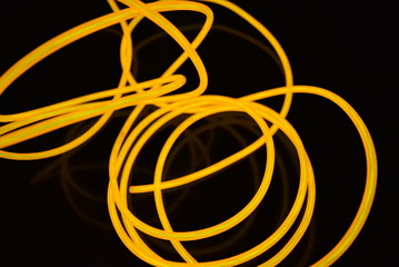 The original yellow lighting of thick electoluminescent wires and lines. Graphic abstract light background with interesting combination of shapes and textures.