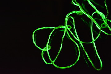 Toxic green lime lighting with a specific pattern. Woven filaments, cable, wires with outgoing light. Neon electroluminescent wire in the form of night lighting.