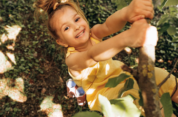 Outdoors image of adorable cute blond little girl playing and smiling broadly at nature background....