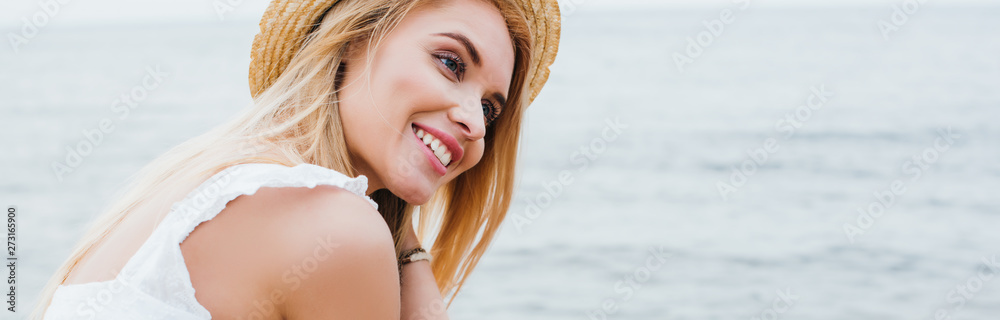 Wall mural panoramic shot of pretty young woman smiling near sea