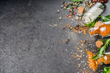 Cooking food background with herbs, olive oil and spices, black stone concrete background above copy space