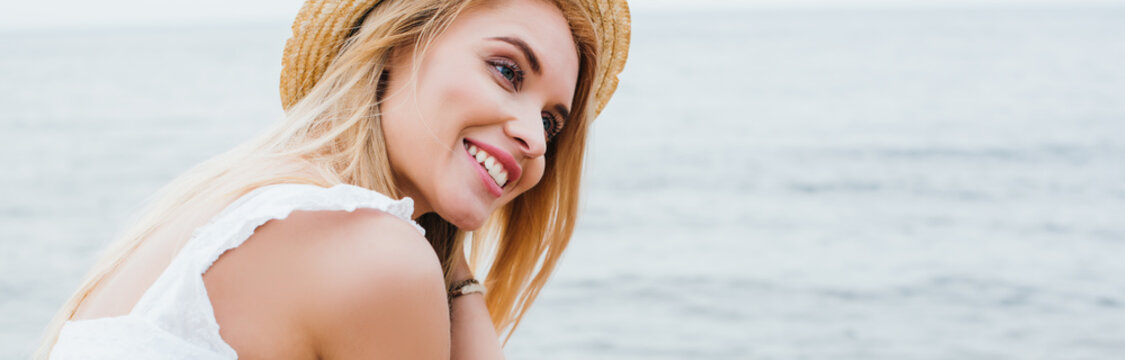 panoramic shot of pretty young woman smiling near sea