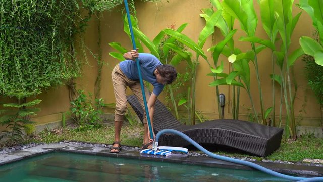 Young man professional swimming pool cleaner does pool cleaning service