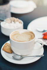 Cup of coffee on black table background with beautiful latte art heart shaped. Breakfast concept.