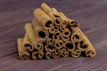Cinnamon sticks piled on a dark wooden table. Spice cinnamon aromatic closeup. Cinnamomum verum...