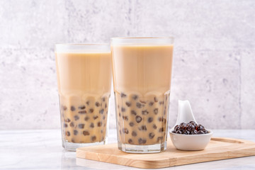 Popular Taiwan drink - Bubble milk tea with tapioca pearl ball in drinking glass on marble white table wooden tray background, close up, copy space
