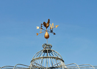 golden weather cock wind compass on the top of a gazebo
