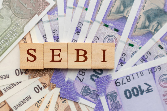 SEBI in wooden block letters on Indian Currency.