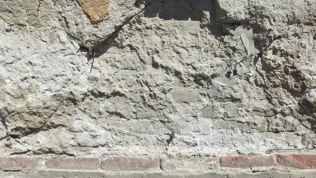 Bad foundations on old house cracked plaster facade wall with brick background under peeled cement, with motion 