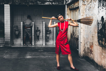 Fototapeta na wymiar Portrait images of Girl wearing red Cheongsam dress Standing and holding a broom For cleaning at the old public restrooms, to instagram concept.