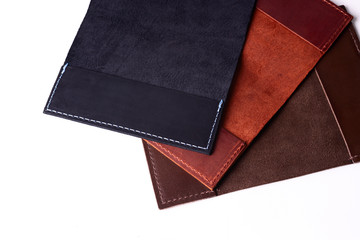 Three handmade leather passport covers isolated on white background. Closeup view. Covers are dark blue, red, brown and opened.