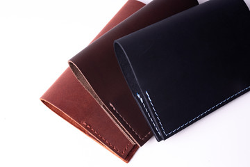 Three handmade leather passport covers isolated on white background. Covers are closed. Closeup view. Covers are dark blue, red and brown.