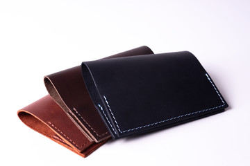 Three handmade leather passport covers isolated on white background. Covers are closed. Closeup view. Covers are dark blue, red and brown.